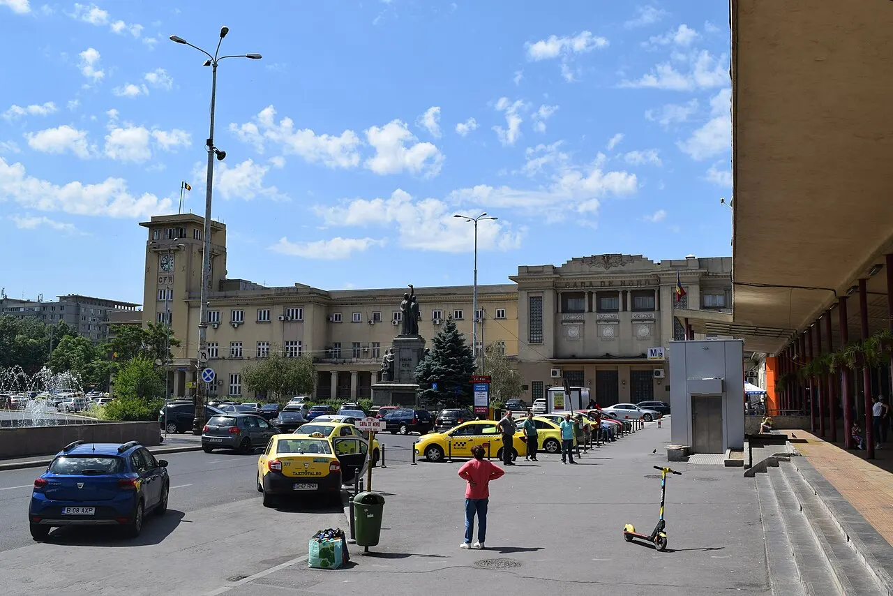 The facade of Gara de Nord, Bucharest's main railway station, with travellers and taxis on the forecourt