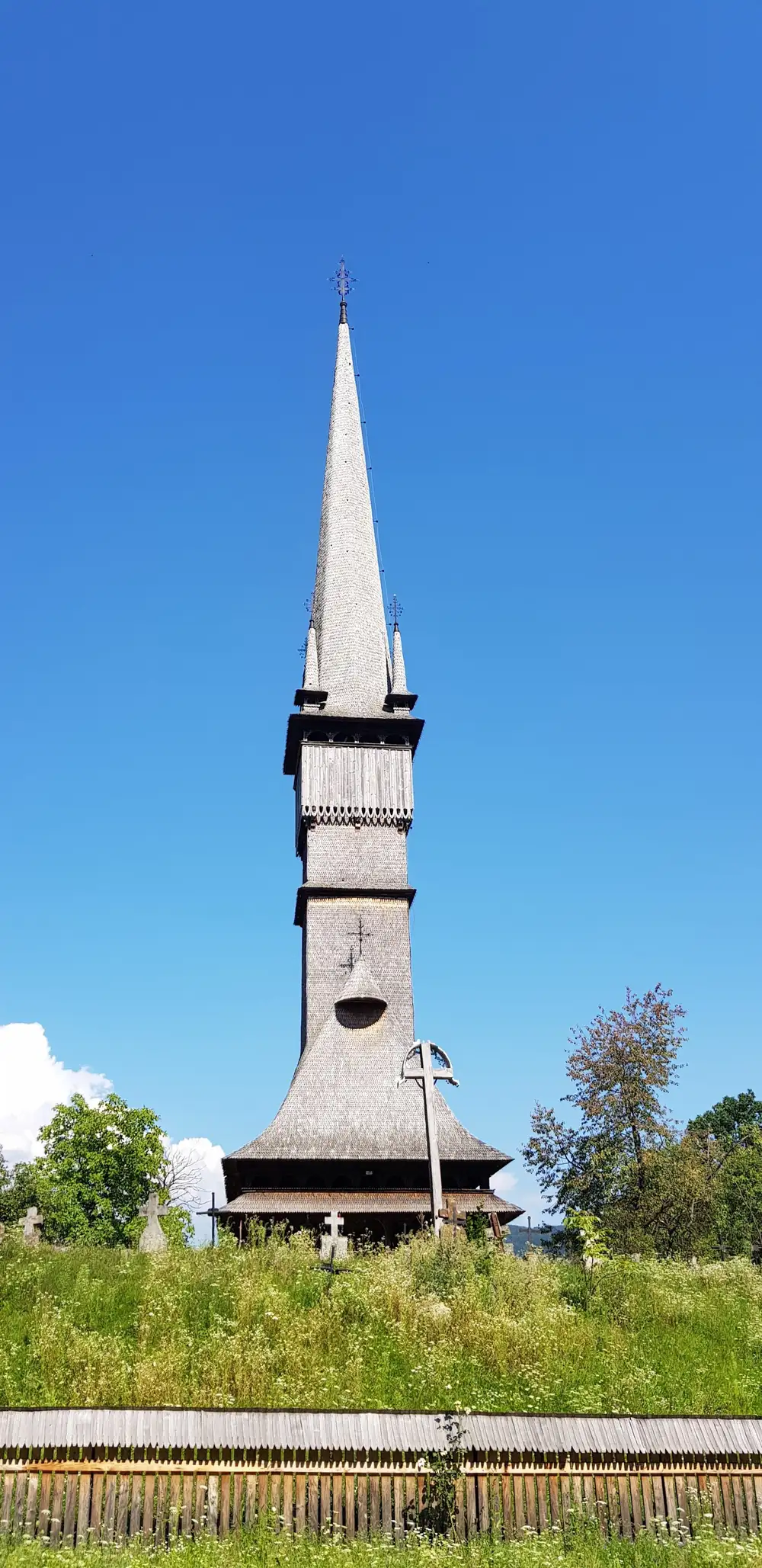 The Surdesti wooden church, a very tall dark timber church with an extremely long slender spire, seen from below