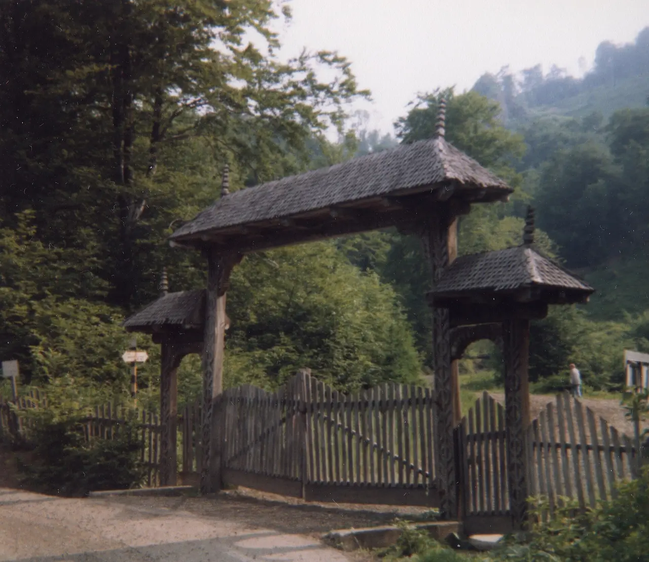 A tall carved wooden entrance gate in a Maramures village, its posts covered in rope-twist and rosette motifs