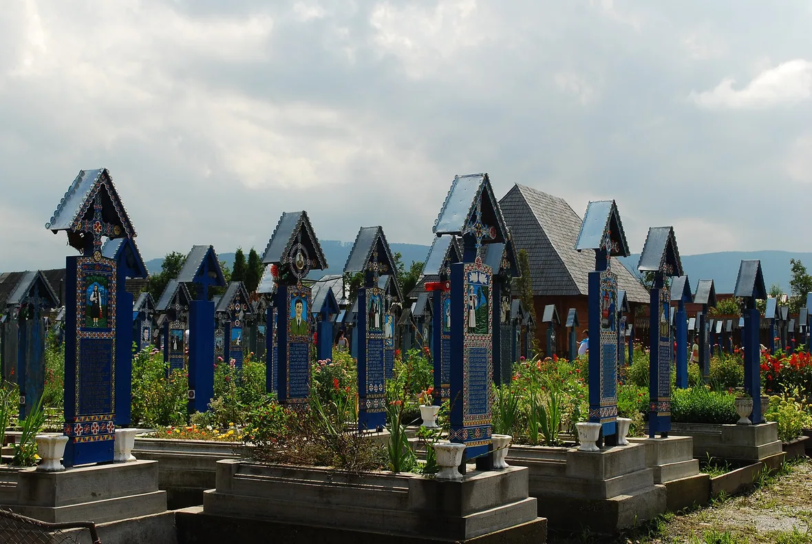 Rows of tall blue painted wooden crosses with small portrait scenes at the Merry Cemetery in Sapanta