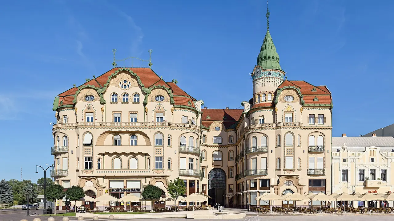 The Black Eagle Palace in Oradea, a large ornate Art Nouveau building with curved gables and pale facades on Union Square