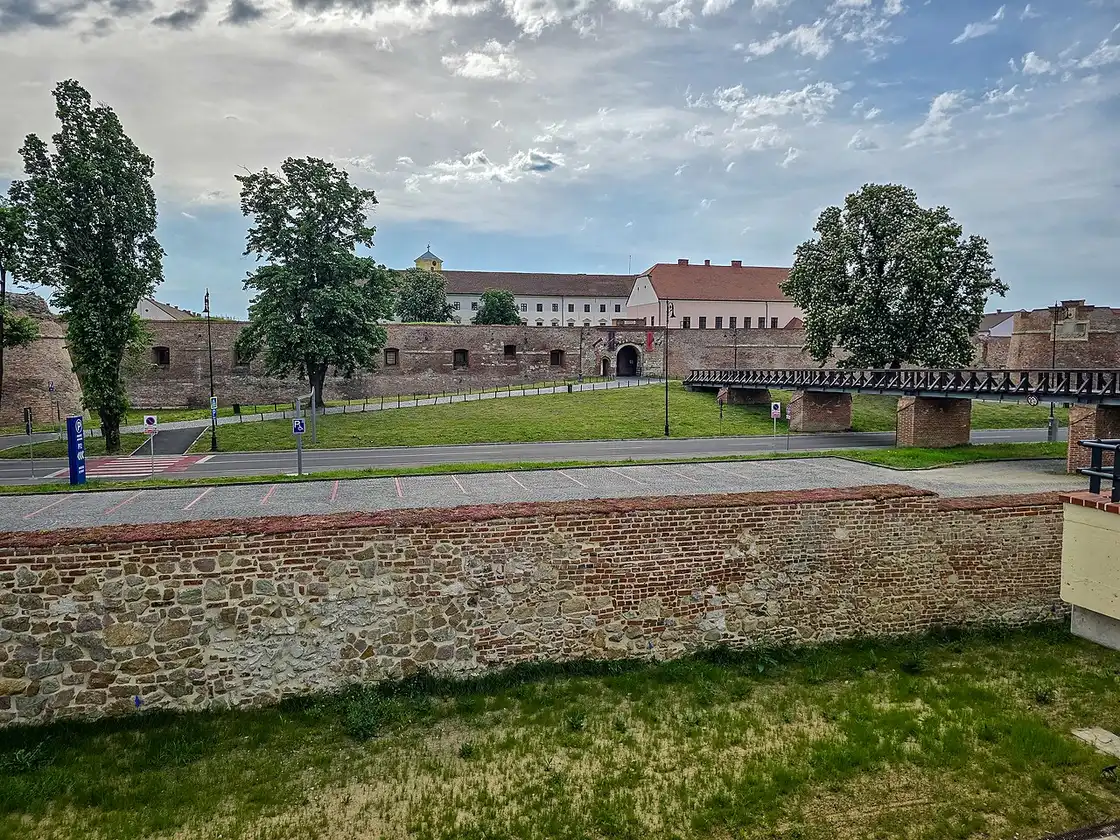 A restored brick bastion and wall of Oradea Fortress under a blue sky, part of the star-shaped citadel in the city centre