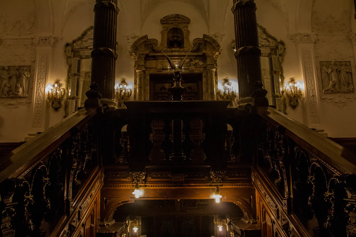 A richly decorated room inside Peles Castle with wood-panelled walls, period furniture, paintings and an ornate ceiling