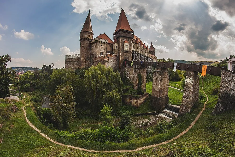 Corvin Castle at Hunedoara with its red-roofed towers and the long wooden bridge crossing to the gate