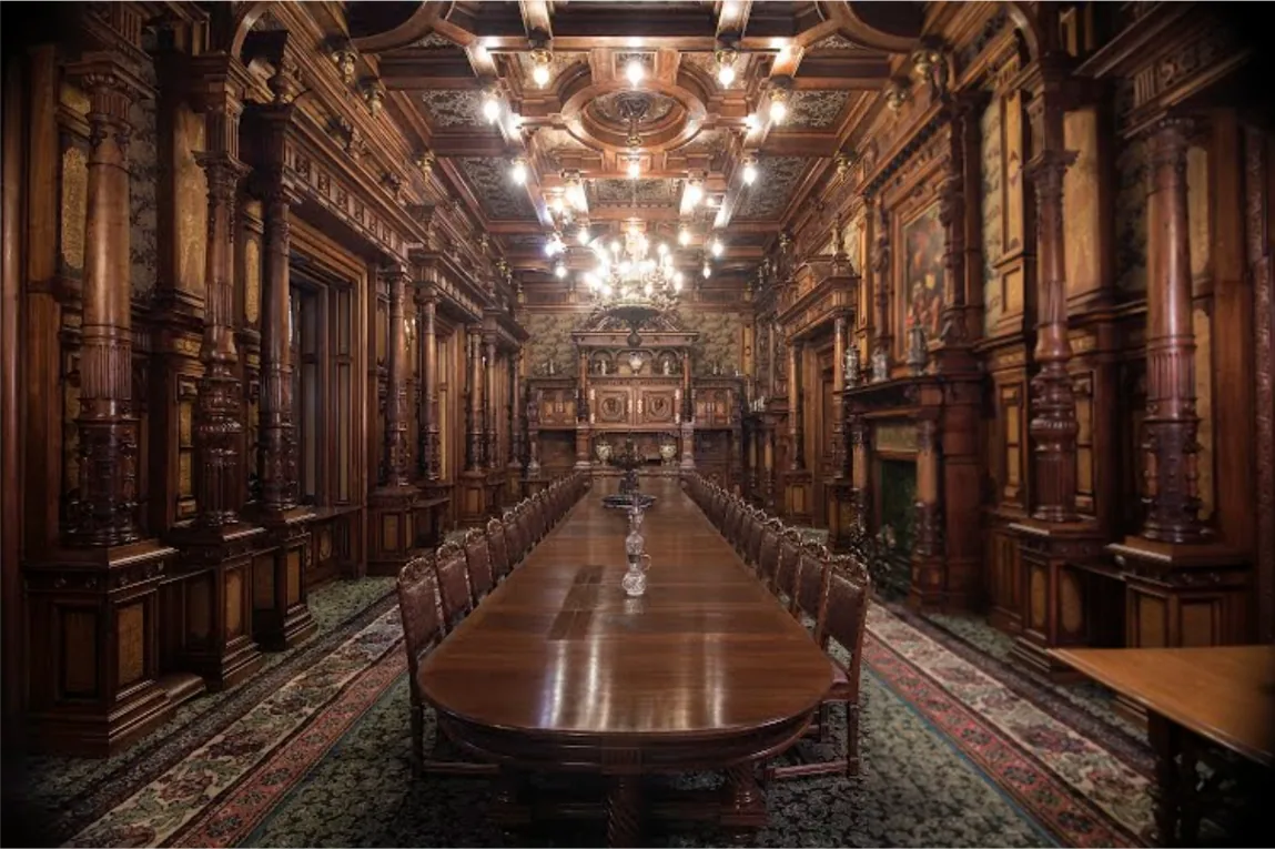 The royal dining room in Peles Castle, a long polished table under carved walnut panelling and a coffered ceiling