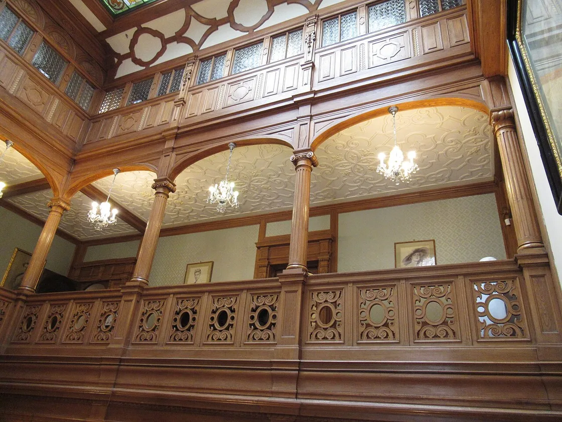 A carved oak gallery on the upper floor of Pelisor, arcades and fretwork balustrades looking down into the room below