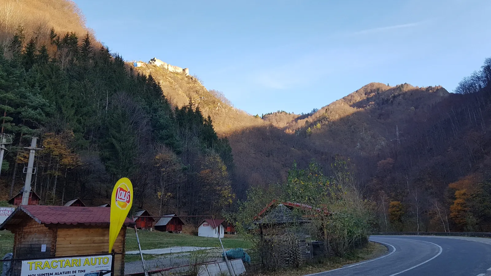 The elongated stone ruins of Poenari Castle on a wooded ridge above the Arges gorge, walls and towers broken against the sky