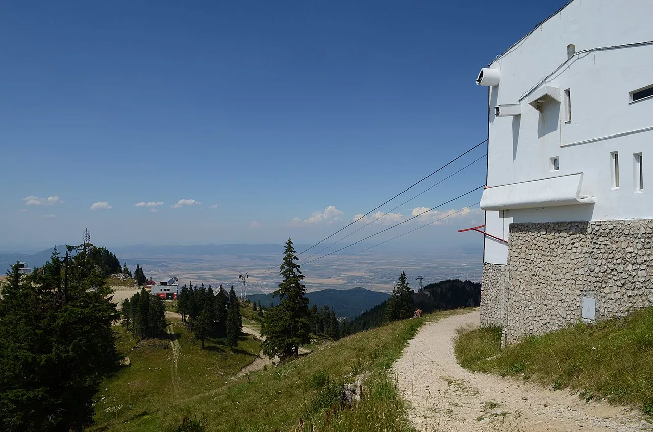 The white upper station of the Poiana Brasov cable car high on Postavaru, its haulage cables running down the mountain towards the Brasov plain far below