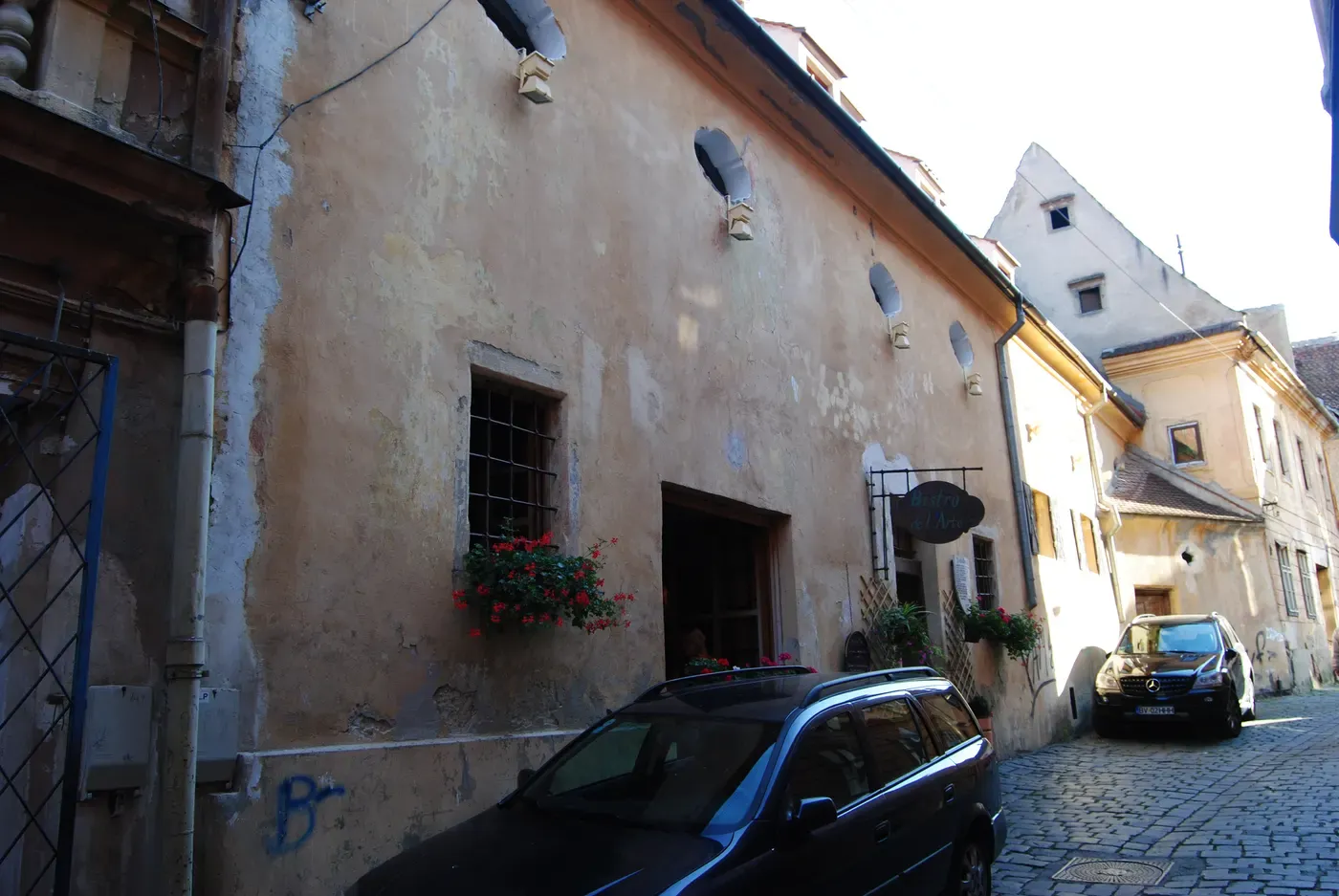 The weathered facade of a centuries-old building on Piața George Enescu in Brașov's Old Town, with the Bistro de l'Arte sign above the entrance