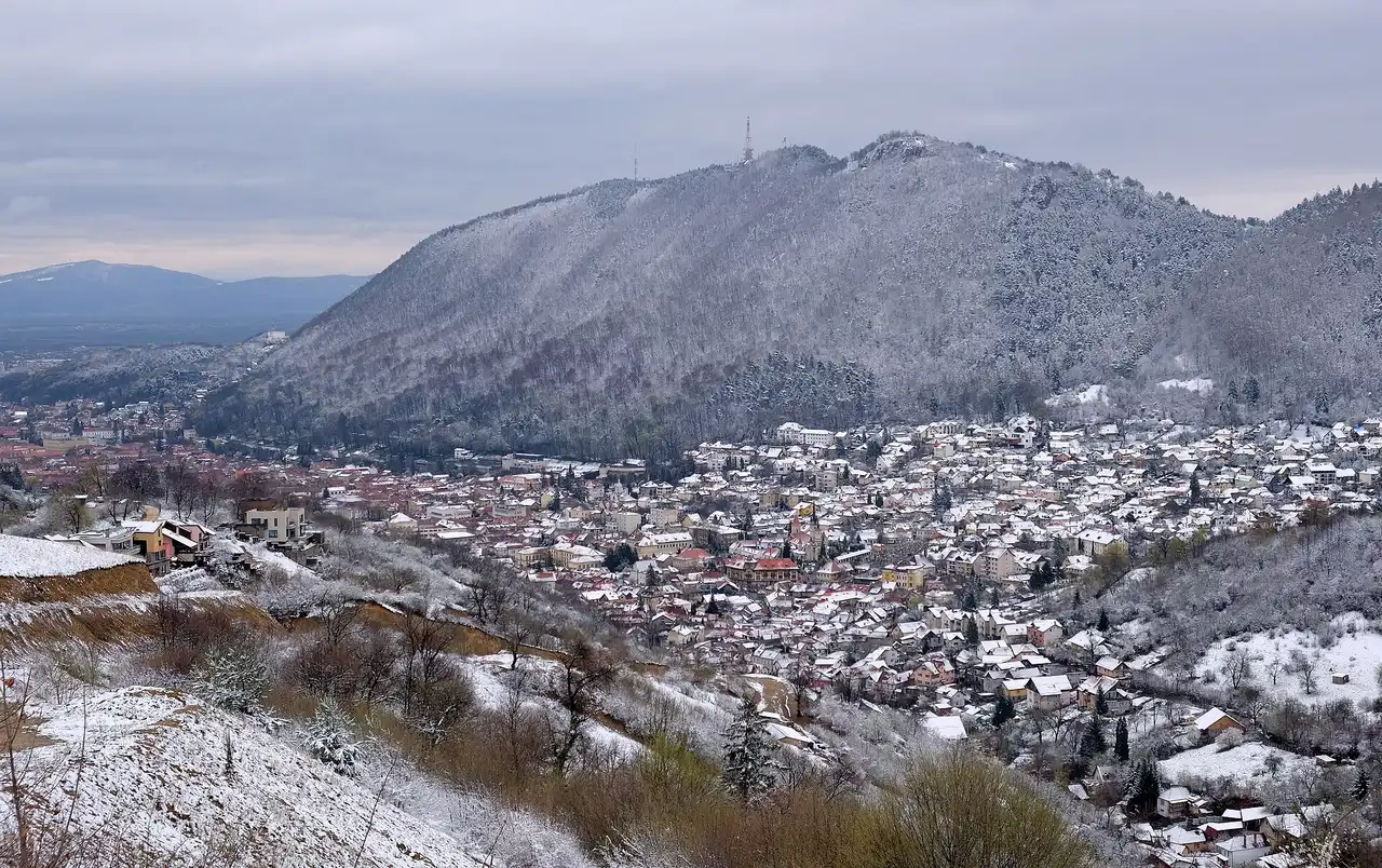 The red rooftops of Brasov old town in its valley below the wooded mountains