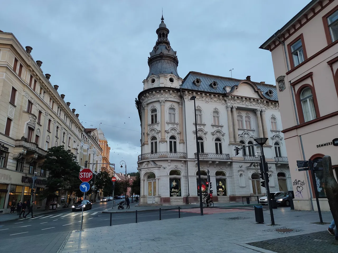 An ornate historic building on a central street of Cluj-Napoca at dusk