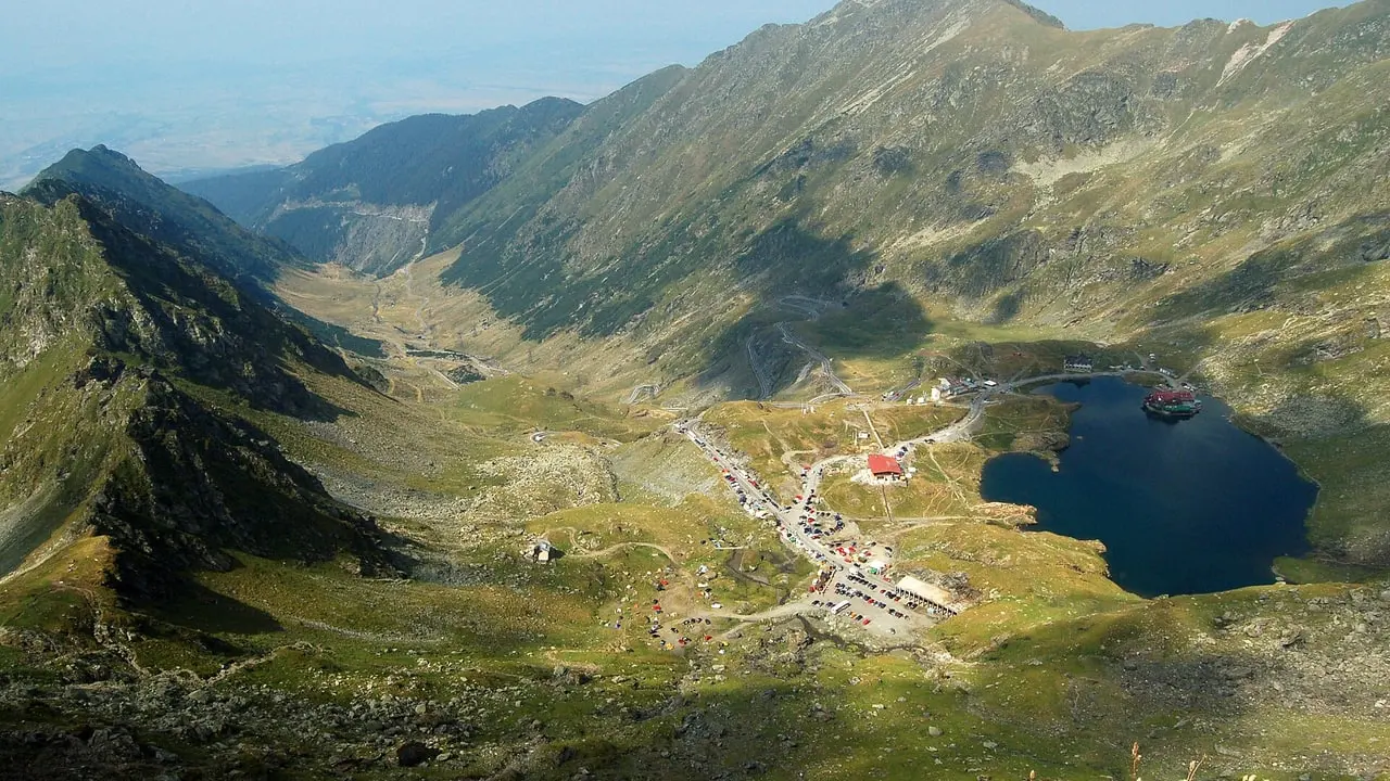 Balea Lake and the Transfagarasan switchbacks seen from above, the road dropping north into the valley