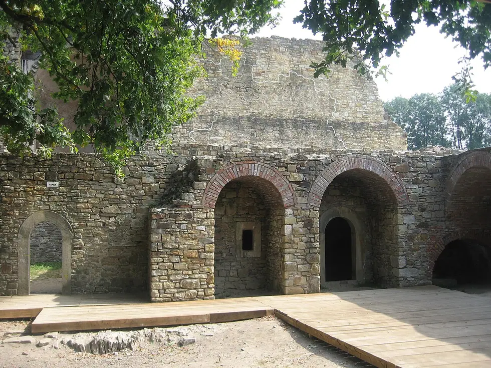 Restored stone ruins inside Suceava's Cetatea de Scaun, with brick-arched vaults and a wooden walkway crossing the old chambers
