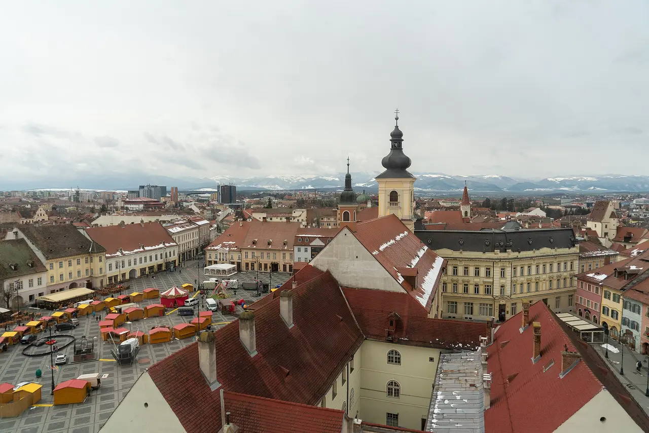 Rooftop view over the Large Square of Sibiu with the snow-dusted Carpathian mountains on the horizon, an alternative base to Bucharest