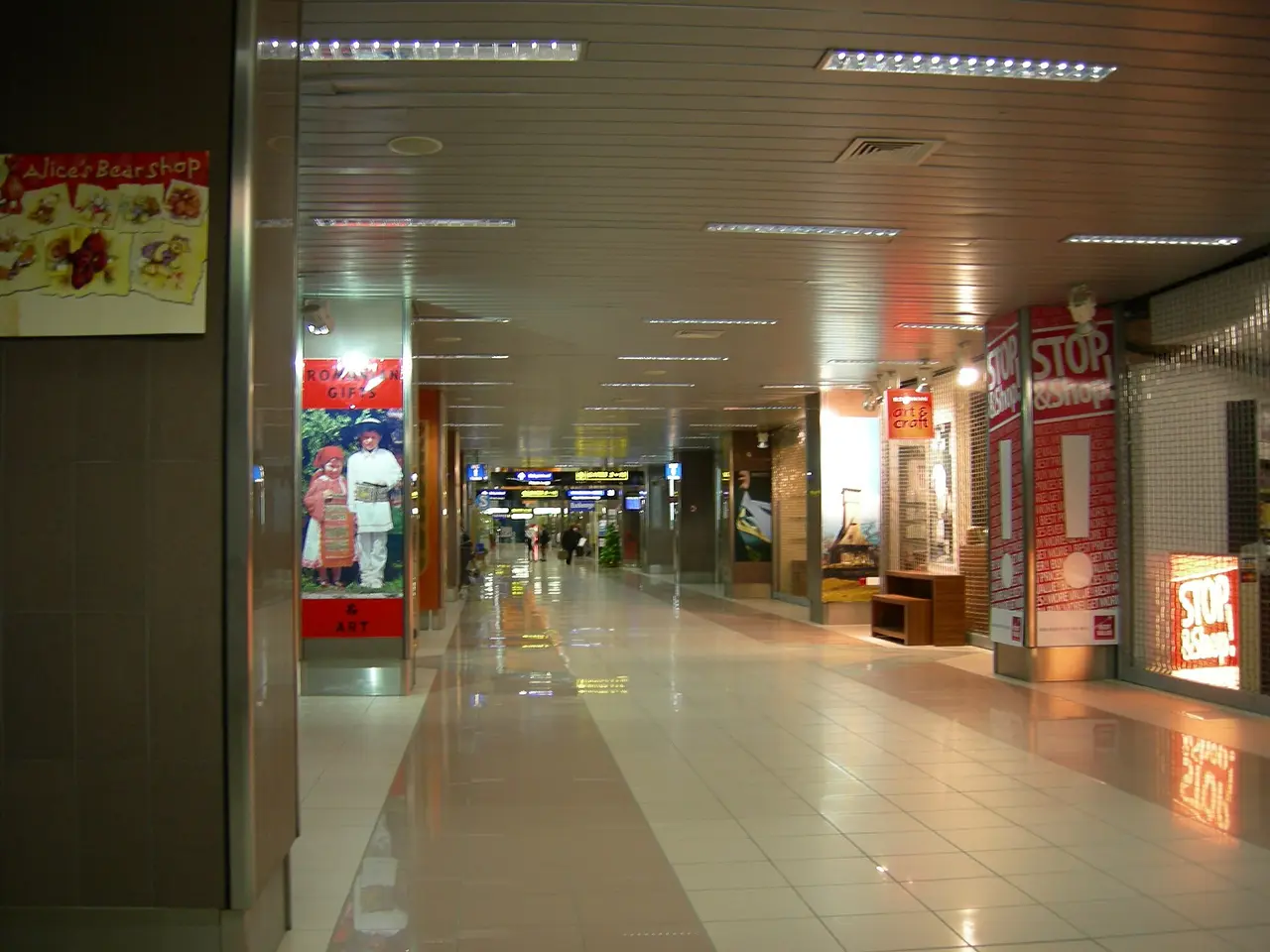 The interior concourse of Bucharest Henri Coanda (Otopeni) airport, a tiled walkway lined with shops leading to the departure gates