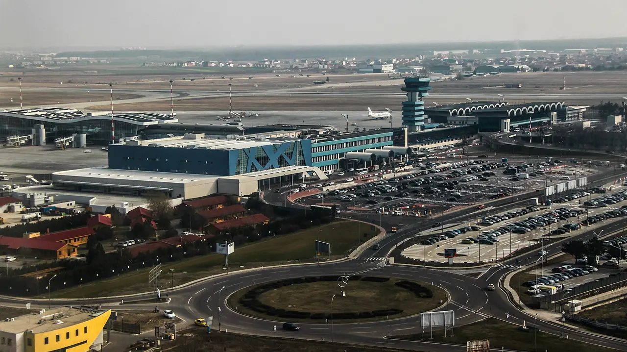 Aerial view of Bucharest Henri Coanda (Otopeni) International Airport, with terminals, the blue control tower, aircraft on the apron and car parks below