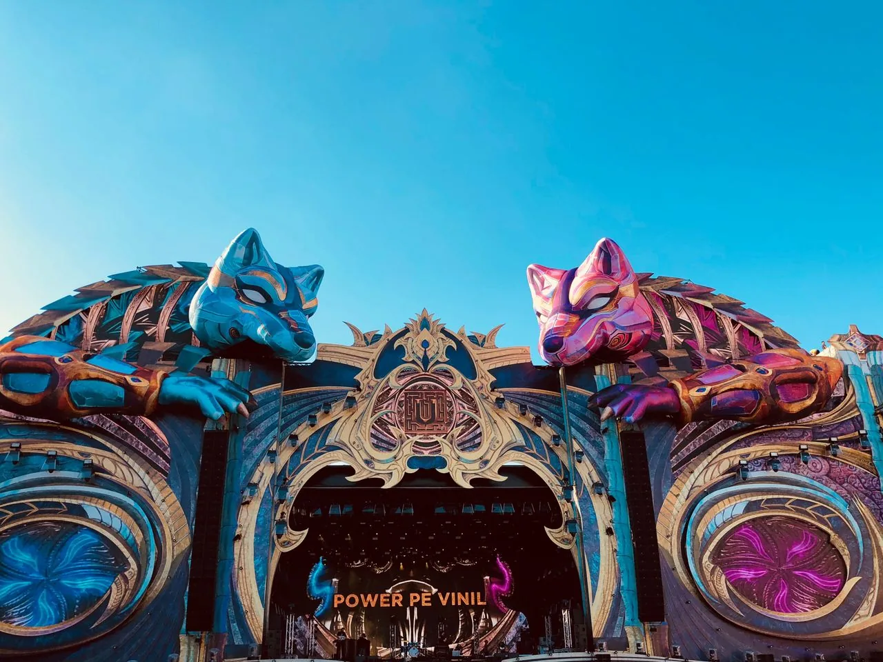 The main stage of the Untold festival in Cluj-Napoca, a huge carved arch topped by two giant blue and pink wolf heads against a clear evening sky