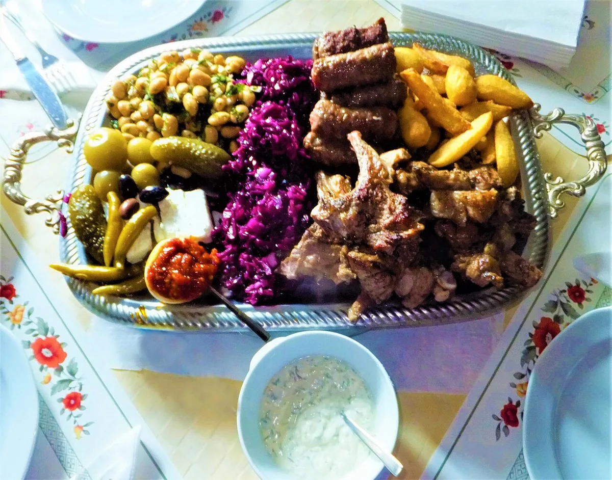 A Romanian mixed grill plate with mici, grilled meats and garnish, the kind of hearty sit-down meal that costs well under a Western equivalent