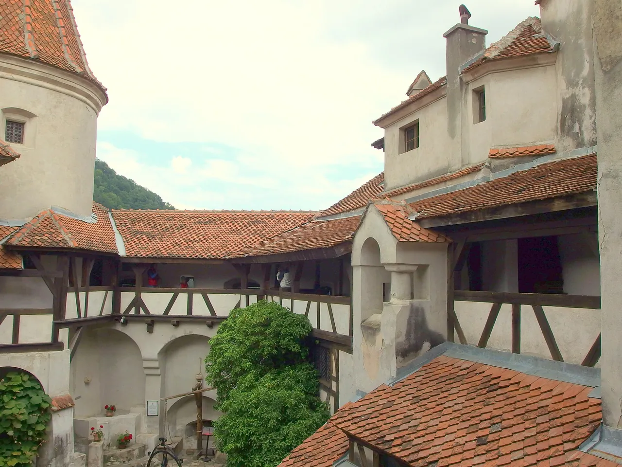 The inner courtyard of Bran Castle with whitewashed walls, timber galleries and steep tiled roofs stacked close together
