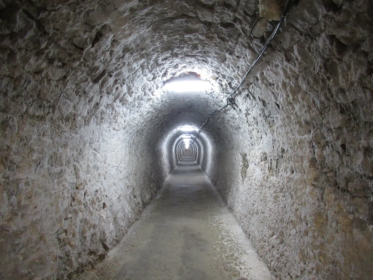 The long arched Franz Josef access gallery cut through grey rock salt, lit by a line of lamps receding into the distance