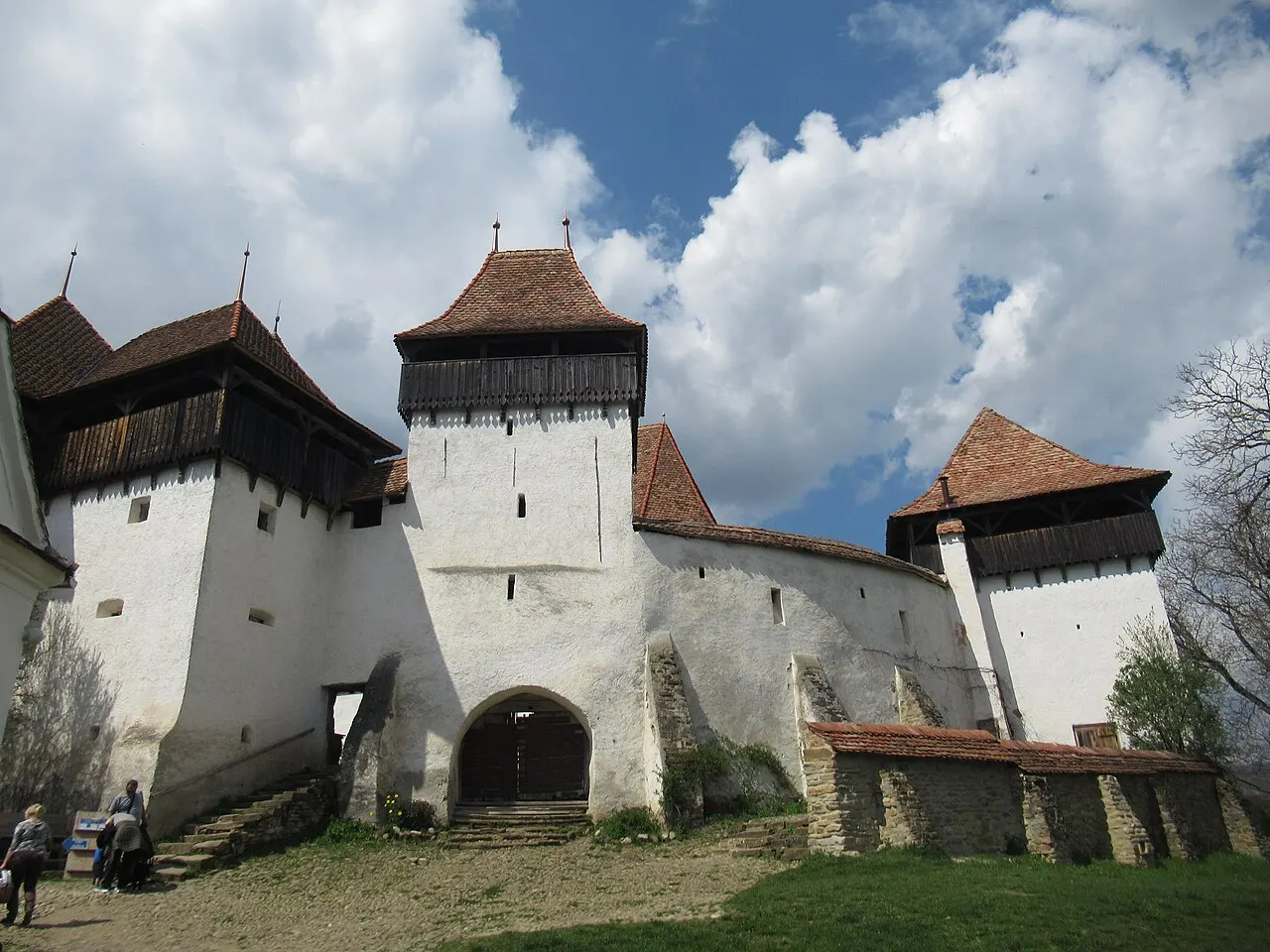The whitewashed fortified church of Viscri with its square defensive towers and wooden galleries under a blue sky