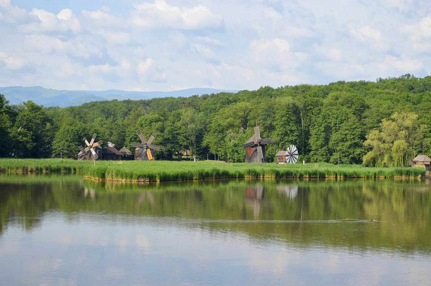 Two wooden windmills reflected in Lake Dumbrava at the ASTRA open-air museum outside Sibiu