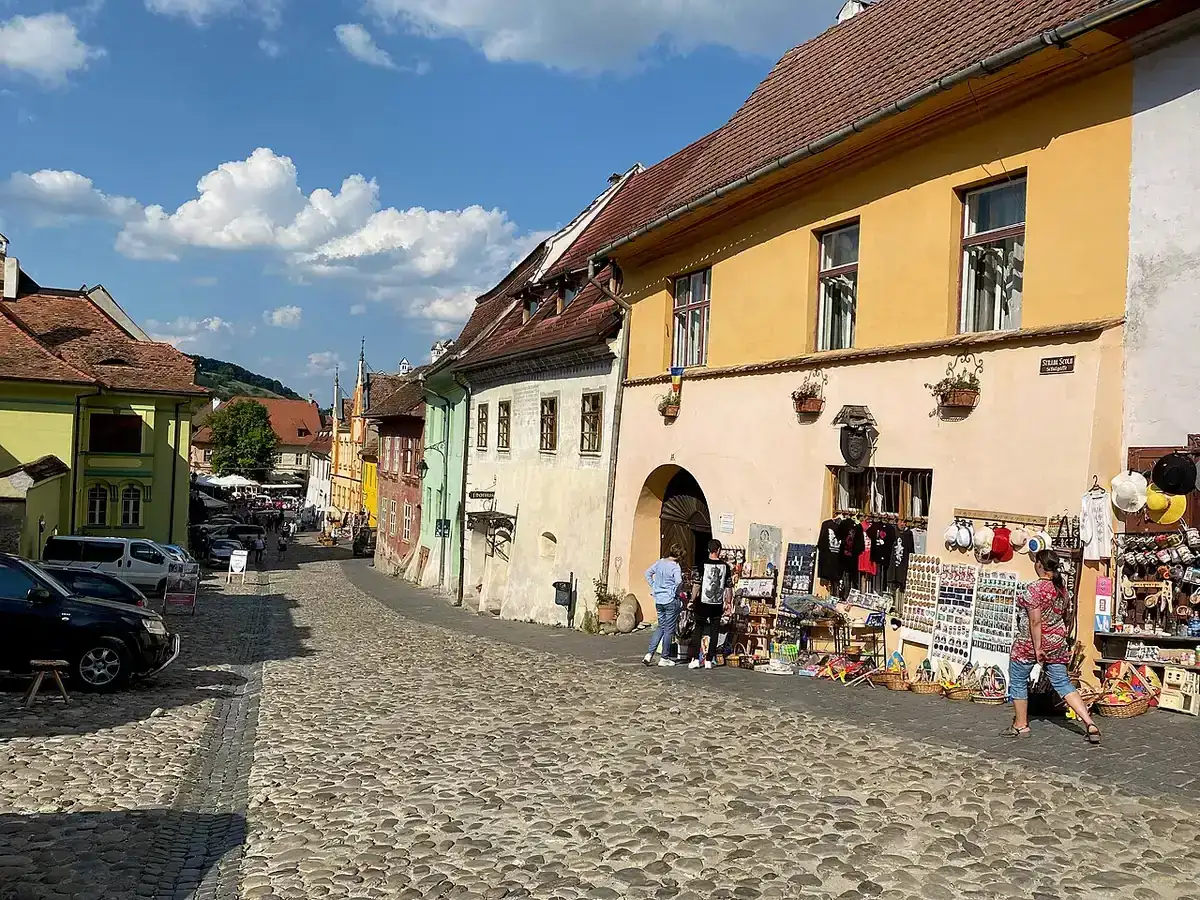 A steep cobbled street in the Sighisoara citadel lined with old Saxon houses in ochre and green