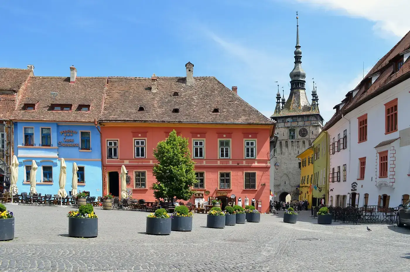 Piata Cetatii, the citadel square in Sighisoara, ringed by pastel houses with the Clock Tower rising behind