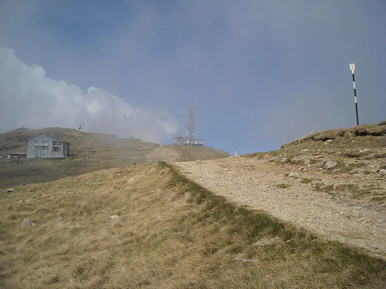 The bare, grassy top of the Bucegi plateau above Sinaia, a mountain chalet and a tall transmitter mast on the skyline under a big sky