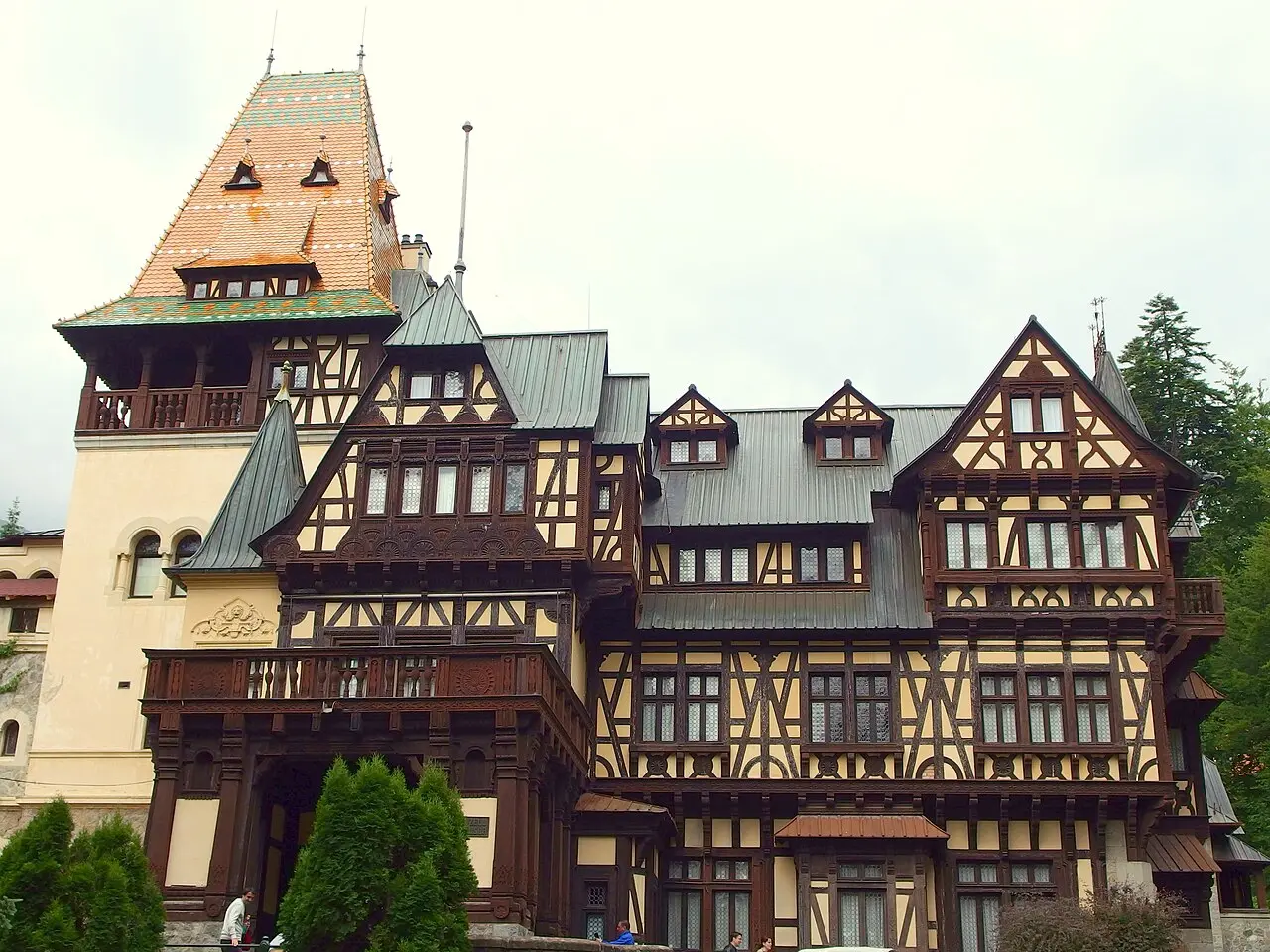 A half-timbered royal building in the forested grounds of the Peles estate above Sinaia, dark timber framing and a tower with a coloured tiled roof