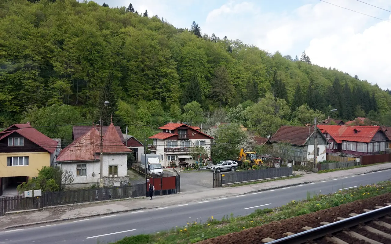 Colourful wooden houses in Predeal with snow on the roofs and forested hills behind