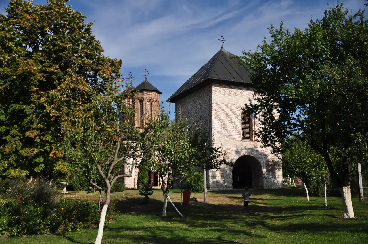 The stone-and-brick bell tower of Snagov Monastery with its arched gateway opening onto the island lawn