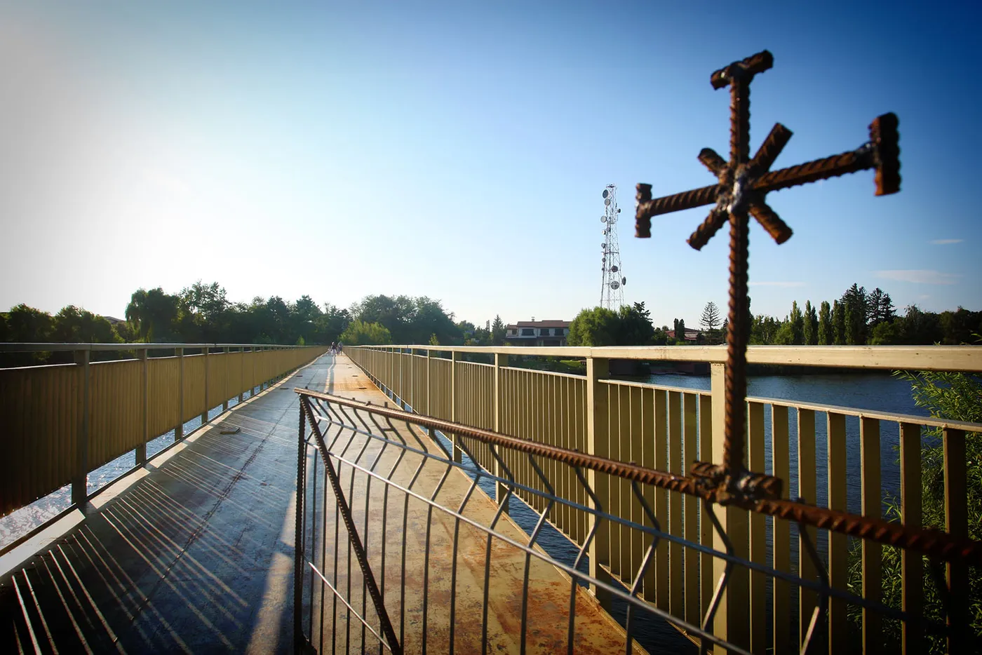 The pedestrian footbridge over Lake Snagov with two moored rowing boats in the foreground and willows hanging over the water