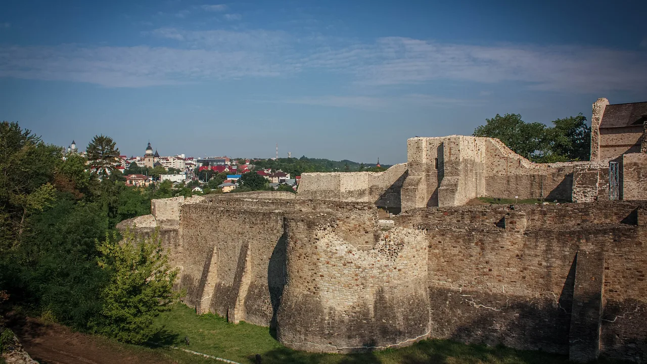The reconstructed walls and round tower of Suceava Seat Fortress on its hill above the city, green forest behind