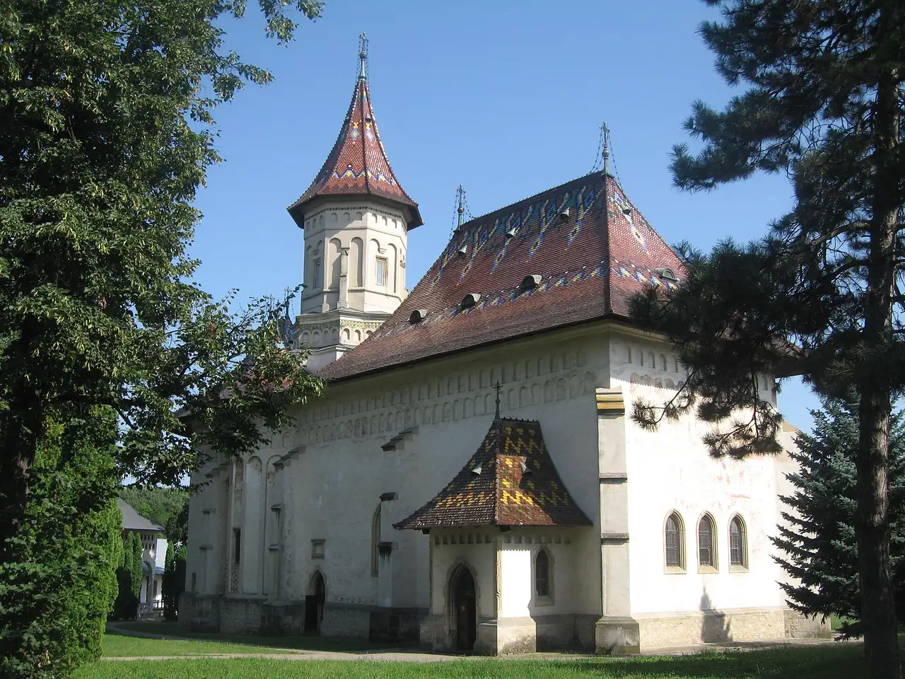 The Saint John the New Monastery complex in Suceava, church domes and walls behind trees in the old centre