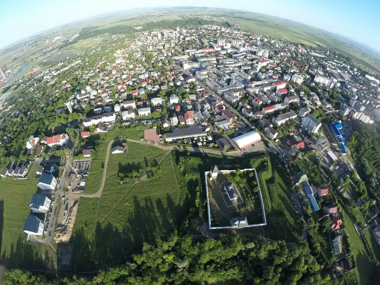 Aerial view of Zamca Monastery with its star-shaped walls and church, the city of Suceava spread beyond