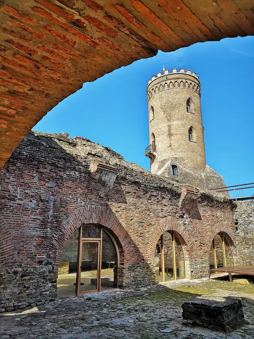 The Chindia Tower seen through a brick archway above the ruined walls of the Princely Court in Targoviste, blue sky beyond