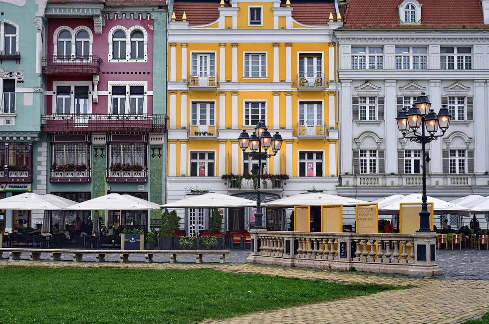 Piata Unirii in Timisoara, a wide Baroque square lined with restored pastel palaces and the twin-towered Roman Catholic cathedral