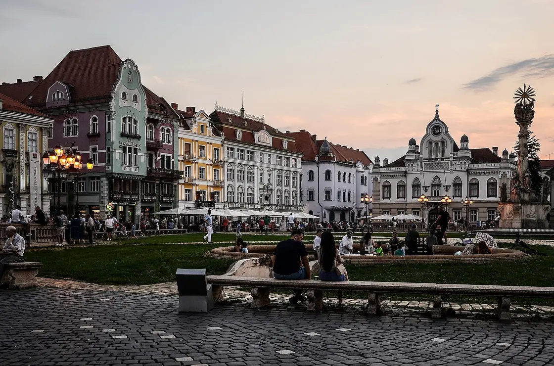 Union Square (Piata Unirii) in Timisoara, a wide Baroque square lined with restored pastel palaces, the heart of the city you leave behind