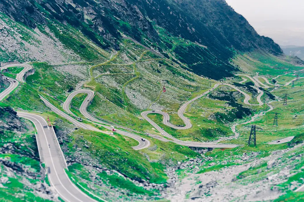 The Transfagarasan road switchbacking in tight hairpins down a green Fagaras mountainside