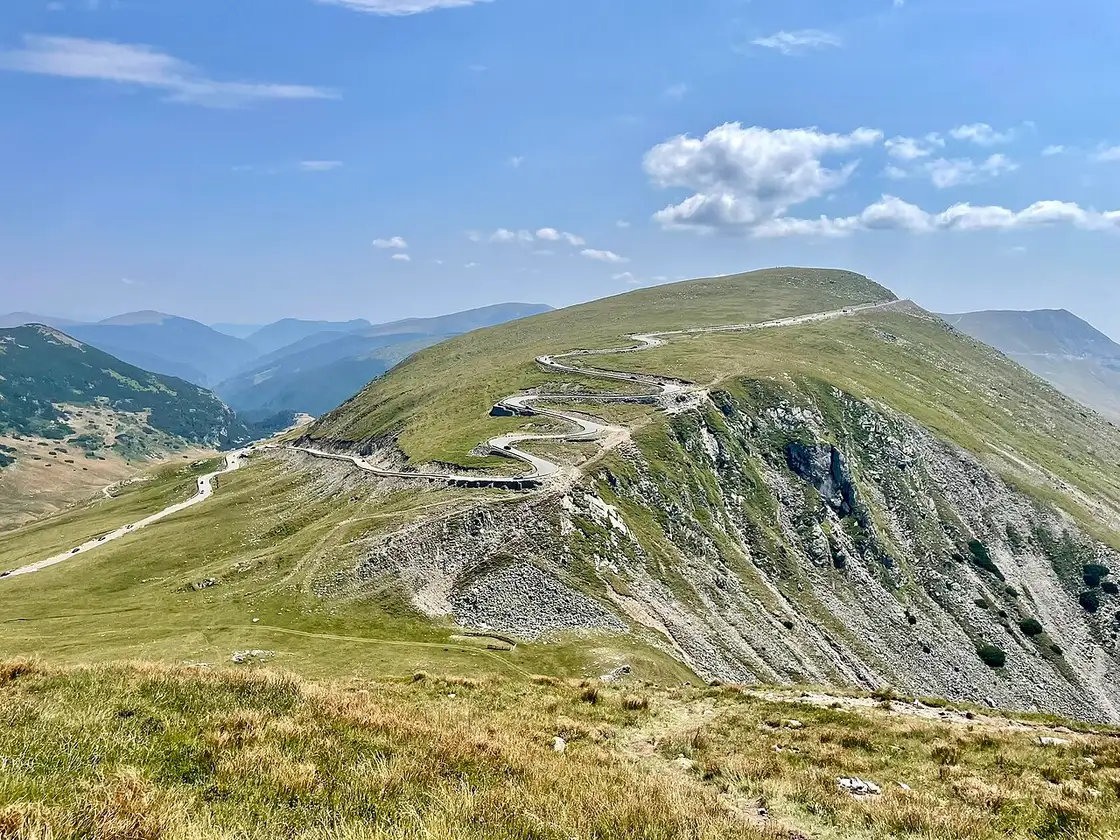 Urdele Pass on the Transalpina with road markers and open mountain ridges under cloud