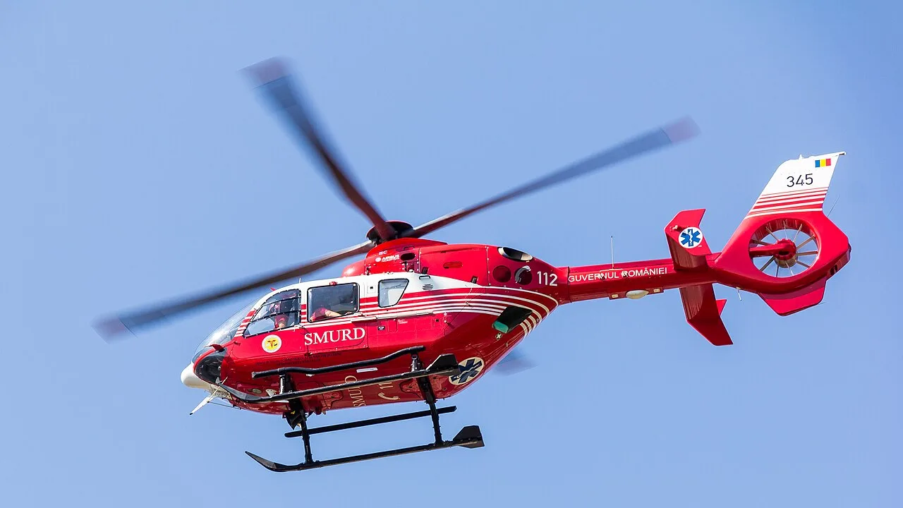 A red SMURD air-ambulance helicopter in flight against a blue sky