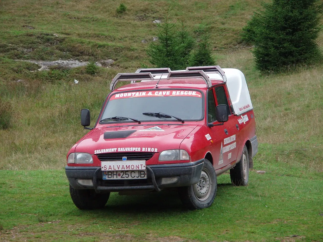 A red Salvamont mountain and cave rescue vehicle parked on a grassy Carpathian slope