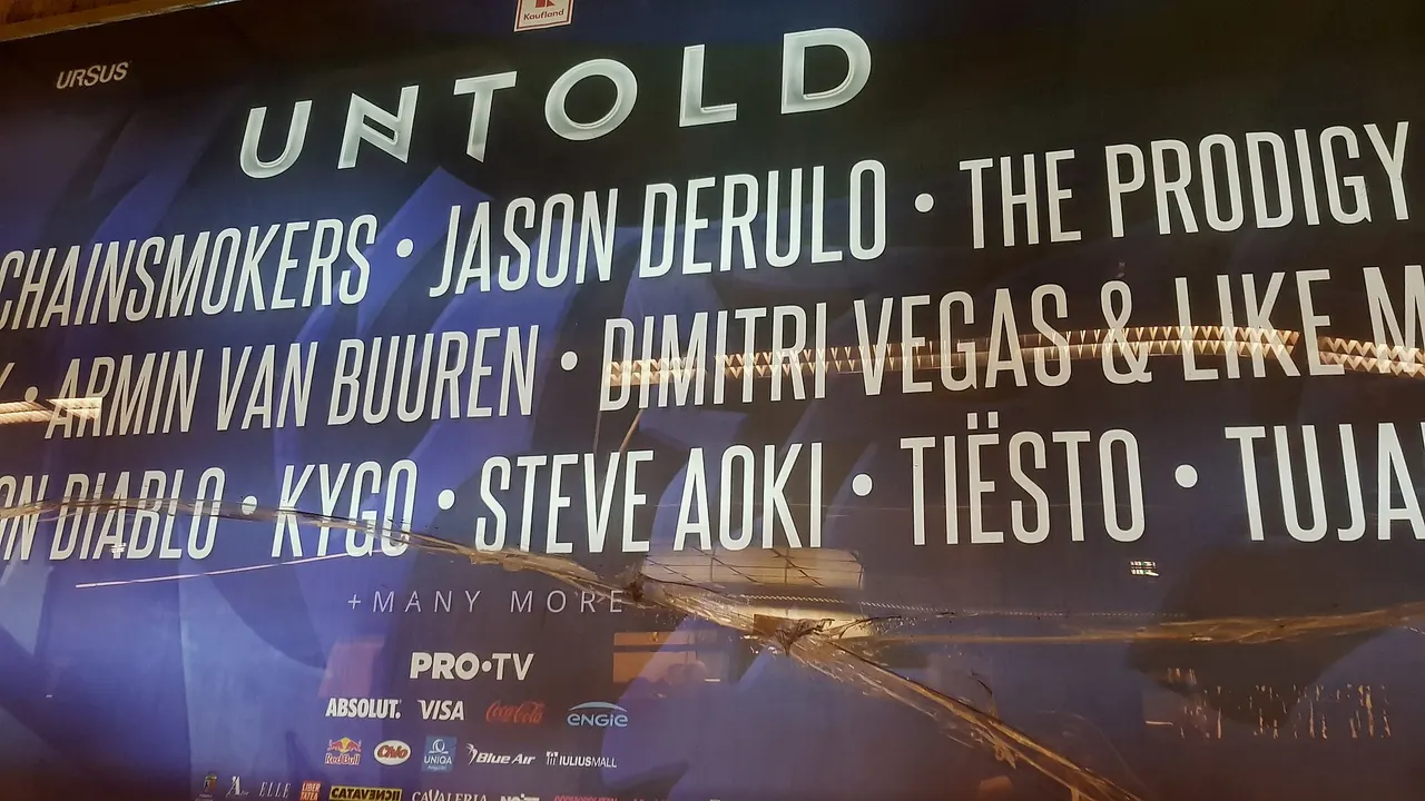 A weathered promotional billboard in Cluj advertising a past Untold edition, listing headline acts under the Untold logo with sponsor branding