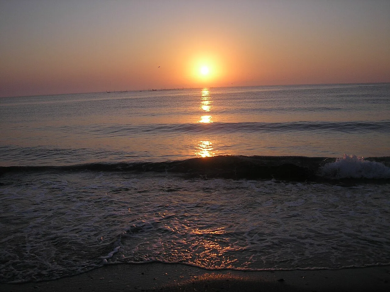 A red and gold sunrise over the Black Sea at Vama Veche, waves catching the light as they break on the shore