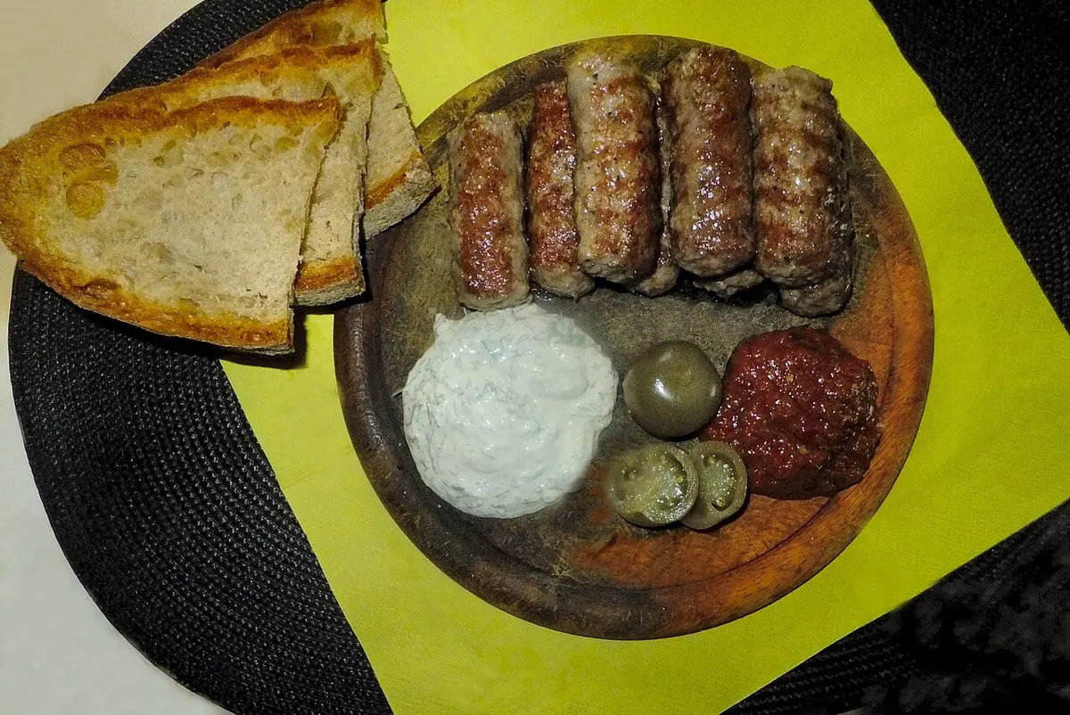 A plate of grilled mici, skinless minced-meat rolls, served with mustard