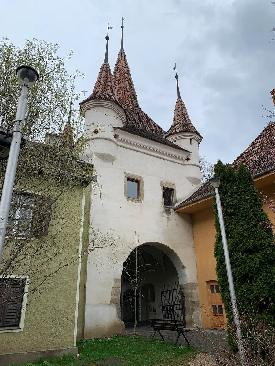 Catherine's Gate (Poarta Ecaterinei) in Brasov, a white medieval gate tower with four corner turrets marking the edge of the old town toward Schei