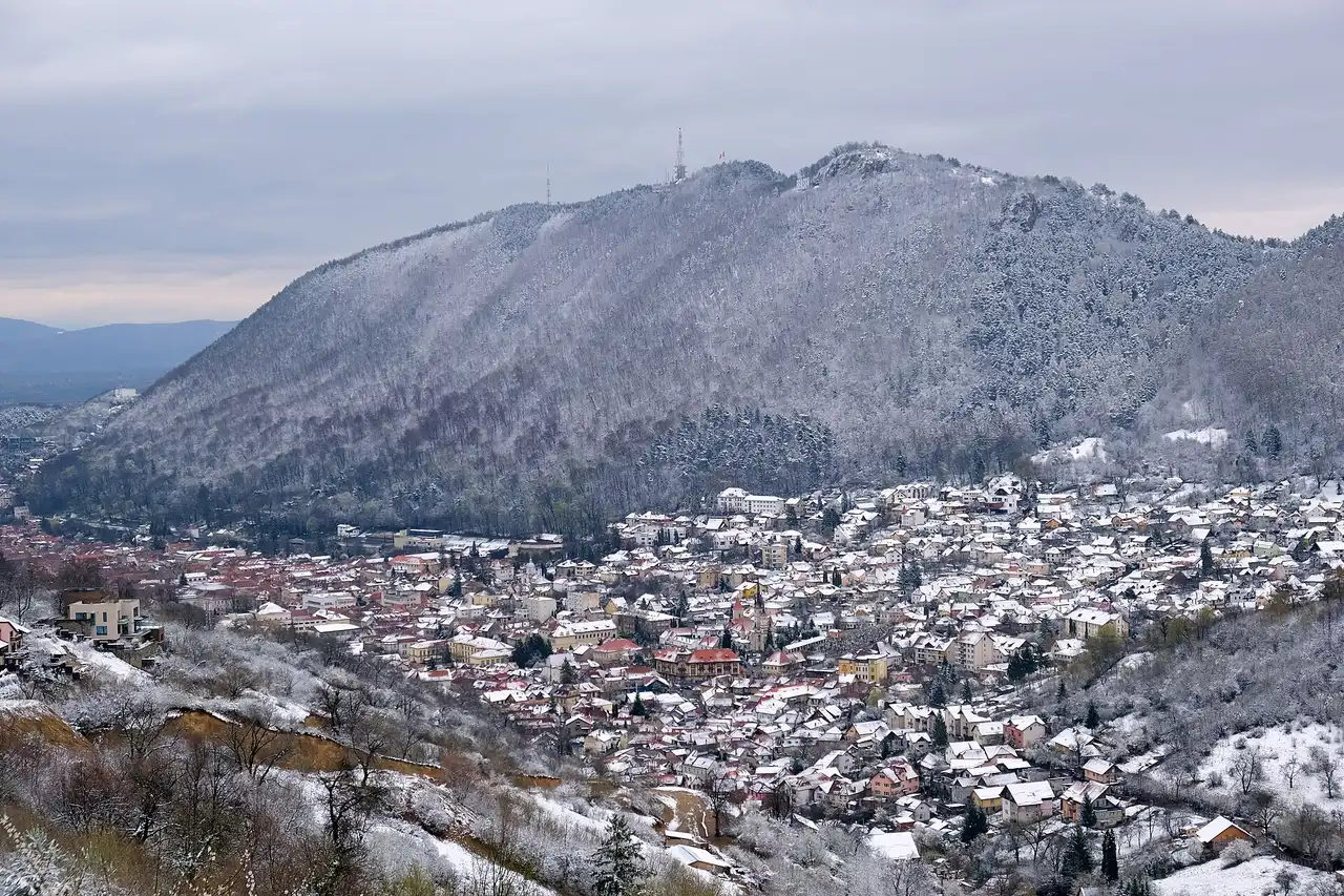 The residential streets of Brasov climbing the valley toward a snow-dusted wooded mountain, showing how the quieter quarters sit away from the flat centre