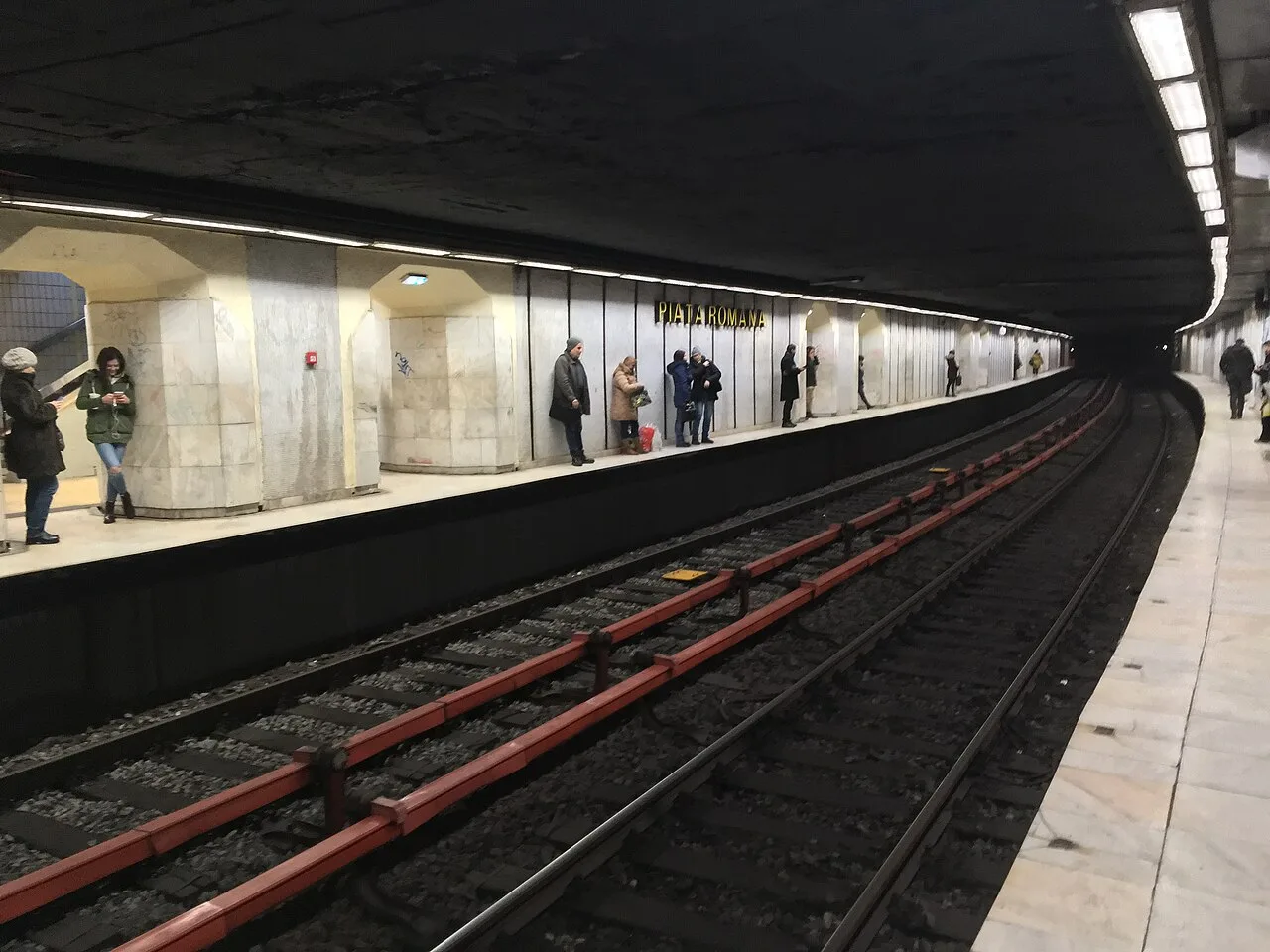 The platform of Piata Romana metro station on the M2 line in Bucharest, passengers waiting by the marble-clad wall