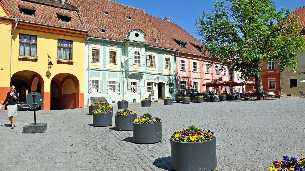 Piata Cetatii, the citadel square in Sighisoara, ringed by pastel Saxon houses with the fortified upper town rising behind